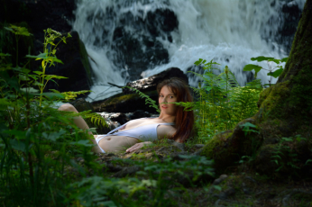 Junge Frau halbliegend am Wasserfall